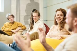 Grupo de jóvenes profesionales compartiendo ideas en un ambiente relajado y creativo de trabajo.